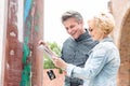 Cheerful middle-aged couple reading map in city