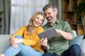 Cheerful Middle Aged Couple Relaxing With Digital Tablet At Home Royalty Free Stock Photo