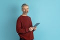 Cheerful middle aged man using digital tablet on blue background Royalty Free Stock Photo