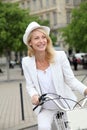 Cheerful middle-aged woman cycling in town