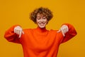 Cheerful middle-aged woman pointing fingers down isolated over yellow background Royalty Free Stock Photo