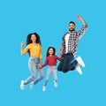 Cheerful Middle Eastern Family Of Three Jumping Over Blue Background