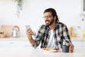 Cheerful middle-eastern man eating healthy food and using phone Royalty Free Stock Photo