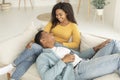 Cheerful millennial african american couple with remote control enjoy free time and tender moment, relaxing
