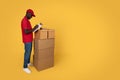 Cheerful millennial african american guy courier in uniform making notes in warehouse, cheks many boxes Royalty Free Stock Photo