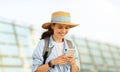 Cheerful millennial caucasian lady tourist in hat with backpack, typing on phone, use online map Royalty Free Stock Photo