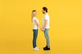 Cheerful millennial caucasian male and female in white t-shirts holding hands, looking at each other Royalty Free Stock Photo