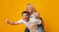 Cheerful millennial couple showing thumbs up, having fun together