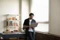 Cheerful millennial employee man in casual standing at office desk