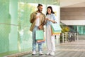 Cheerful millennial european couple with bags enjoy shopping app on smartphone, credit card in mall Royalty Free Stock Photo