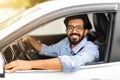 Cheerful millennial indian guy with glasses driving white auto Royalty Free Stock Photo