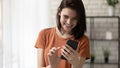 Cheerful millennial woman standing at living room dialing phone number Royalty Free Stock Photo