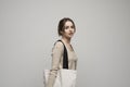 Cheerful millennial woman with a white eco bag standing over white studio background. Lady holding shopper handbag Royalty Free Stock Photo