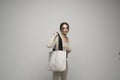 Cheerful millennial woman with a white eco bag standing over white studio background. Lady holding shopper handbag Royalty Free Stock Photo