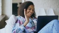 Cheerful mixed race girl having video chat with friends using laptop camera while lying on bed Royalty Free Stock Photo