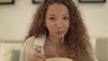 Cheerful mixed race lady with curly hair eats noodles