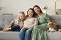 Cheerful mom, grandma, happy girl and dog resting on couch Royalty Free Stock Photo