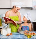 Cheerful mom showing girl recipe of omelette Royalty Free Stock Photo