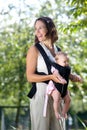 Cheerful mother with baby in sling