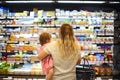 Cheerful mother and baby spending time in shopping in supermarket Royalty Free Stock Photo