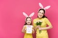 Cheerful mother in bunny ears holding greeting card with happy easter lettering near kid with tulips Royalty Free Stock Photo