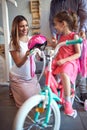 Cheerful mother buying new bicycle and helmet for girl in bike shop