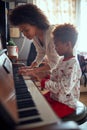 Cheerful mother with child girl on Christmas play music on piano