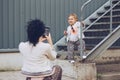 Cheerful mother and daughter having fun in city. A young mother photographs her daughter on a mobile phone. Child posing for