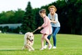 cheerful mother and daughter playing with golden retriever dog on green grass Royalty Free Stock Photo