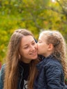 Cheerful mother and daughter smiling sitting in autumn park. Happy family walk. Cute little child playing with parent Royalty Free Stock Photo