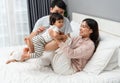 cheerful mother and father playing and lifting toddler baby with her leg on bed, happy family Royalty Free Stock Photo