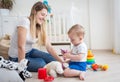 Cheerful mother and her baby boy on floor playing with toys Royalty Free Stock Photo