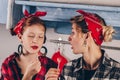 Cheerful mother and her daughter laugh, have fun while eating candy in the kitchen. They are in red clothes and headbands. Red Royalty Free Stock Photo