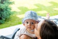 Cheerful mother hugging, cuddling and cheek kissing lovely blue eyed baby boy Royalty Free Stock Photo