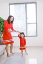 Cheerful mother little daughter standing in living room at home moving dancing to favourite song together