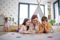 Cheerful mother of three little children reading them book at home. Royalty Free Stock Photo