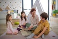 Cheerful mother of three little children reading them book at home. Royalty Free Stock Photo