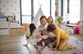 Cheerful mother of three little children receiving hugs from them at home. Royalty Free Stock Photo