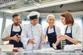 cheerful multicultural confectioners in aprons working