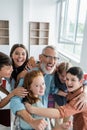 cheerful multicultural teenagers embracing laughing teacher