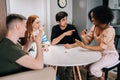 Cheerful multiethnic friends having play cards games for time enjoying board games activity for entertainment at home Royalty Free Stock Photo