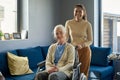 Cheerful multiethnic girl standing by her grandmather in wheelchair