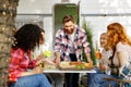 A cheerful multinational company is having fun on a picnic. Multisex friends sitting at the table outdoors celebrating Royalty Free Stock Photo