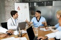 Cheerful multiracial doctors having conversation, using gadgets