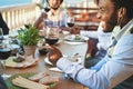 Cheerful multiracial friends eating and drinking wine while wearing protective masks - Focus on black man Royalty Free Stock Photo