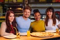 Cheerful multiracial friends having fun eating in pizzeria. Royalty Free Stock Photo