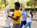 Cheerful multiracial middle aged and older adults enjoying dancing in pairs outdoor at park Royalty Free Stock Photo