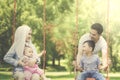 Cheerful muslim family playing on swing