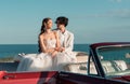 Happy honeymoon trip on cabriolet car. happy bride embrance groom backdrop of the sea Royalty Free Stock Photo