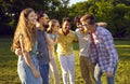 Cheerful and noisy company of young friends relaxing together walking in summer in green park. Royalty Free Stock Photo